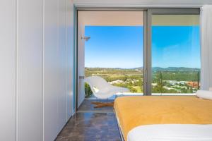 a bedroom with a bed and a white chair at Villa Roca Llisa in Santa Eularia des Riu