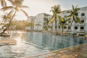 a swimming pool in the middle of a building with palm trees at The Happy Marina Hotel Phú Quốc - Sunset & Ocean View in Phú Quốc