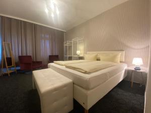 a bedroom with a large white bed and a stool at Deutsches Haus in Malchow