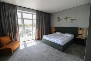 a bedroom with a bed and a chair and a window at Kryla by Shepilska in Dolgoluka