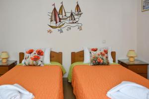 a bedroom with two beds with orange sheets and a sailboat on the wall at Filomeni's house in Kavála