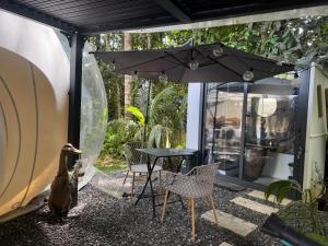a patio with a table and chairs and an umbrella at Bulle skys evasion in Gros-Morne