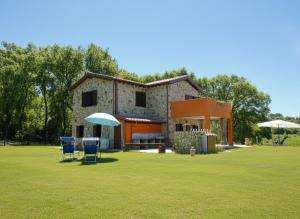 a house with two chairs and an umbrella in a field at Scappo in Umbria, Casale Rusinè in Narni