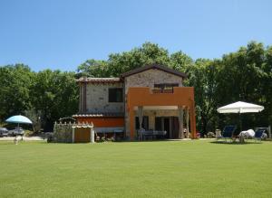 a house with a large yard with chairs and umbrellas at Scappo in Umbria, Casale Rusinè in Narni