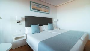 a bedroom with a large white bed with blue pillows at Hotel Bahia Sur in San Fernando