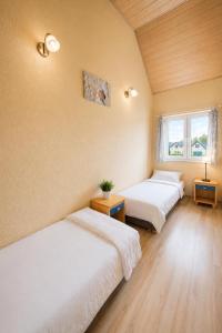 two beds in a room with two windows at DOMKI NA FALI by Baltic Club in Sarbinowo