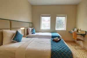 a hotel room with two beds and two windows at Hotel Vilmaris Breeze in Calangute