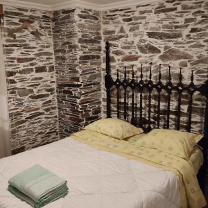 a bed in a room with a stone wall at Cantinho Casal do Rei in Seia +49 photos