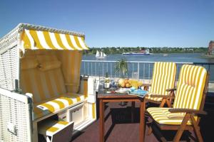 a balcony with two chairs and a table and an umbrella at Hotel AM ELBUFER in Hamburg