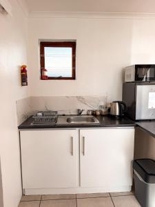 a kitchen with white cabinets and a sink and a microwave at Paterson Place Studios in Hermanus