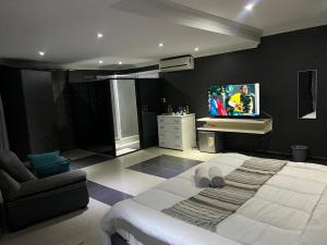 a bedroom with a large bed and a tv on the wall at Acomodações e Serviços TR in Maputo