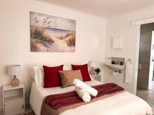 a bedroom with a bed with red and white pillows at Paterson Place Studios in Hermanus