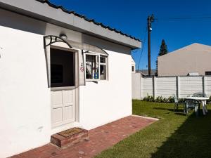 a white house with a white door and a table at Paterson Place Studios in Hermanus