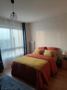 a bedroom with a bed with a red and yellow blanket at Studio avec parking gratuit in Cenon