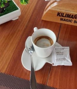 a cup of coffee on a plate with a spoon at Kilimanjaro Magic in Moshi