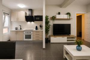 a kitchen with white cabinets and a large television at Nova Suites Viveiro in Viveiro