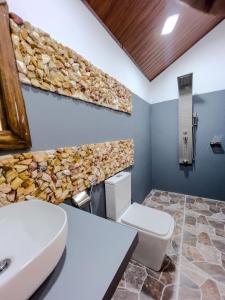 a bathroom with a toilet and a stone wall at Forest River Escape Ella in Ella +65 photos