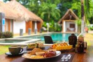 a table with a plate of breakfast food and a pool at SAMADHI Resort & Hydrospa Panglao in Panglao Island