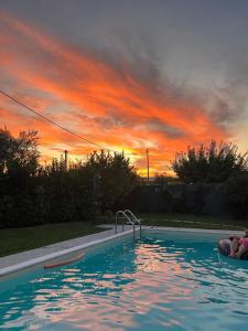a swimming pool with a sunset in the background at Villetta di Laura in Villa San Leonardo