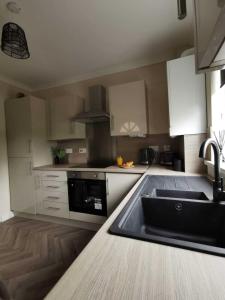 a kitchen with a sink and a stove top oven at Limekilns House in Clydebank +10 photos