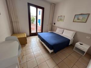 a bedroom with a blue bed and a window at La Conchiglia in Sperlonga