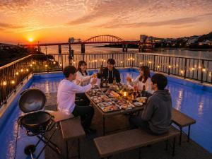 a group of people sitting around a table with food at ゲストハウスMoana 那珂湊おさかな市場徒歩5分,9名可,BBQ可 in Hitachinaka