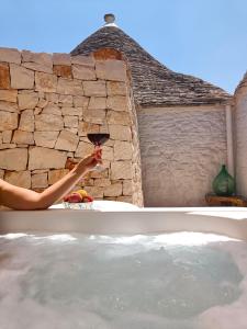 a person holding a glass of wine in a hot tub at Trullo Soave Suite - outdoor jacuzzi in Alberobello