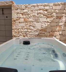 a large bath tub with a stone wall at Trullo Soave Suite - outdoor jacuzzi in Alberobello