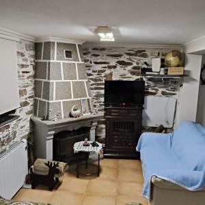 a living room with a stone wall with a stove at Cantinho Casal do Rei in Seia