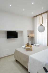 a white bedroom with a bed and a tv at Dimora Don Ferdinando in Naples