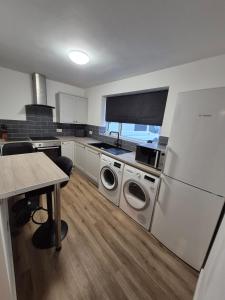 a kitchen with a washer and dryer and a table at Stylish 2-Bed Flat, Minutes to Southport Centre in Southport
