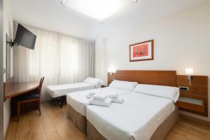 a hotel room with two beds and a desk at Hotel Longoria Plaza by Pandora Hoteles in Oviedo