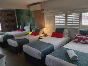 a room with four beds with red and green pillows at Airway Motel in Brisbane