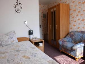 a bedroom with a bed and a couch and a chair at Hotel Garni am Heuberg in Eschwege