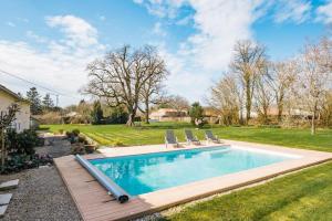 a swimming pool with a deck and chairs in a yard at Villa nest in Saint-Sauvant