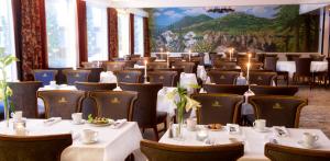 una sala da pranzo con tavoli e sedie bianchi di Vinger Hotell a Kongsvinger