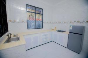 a white kitchen with a sink and a refrigerator at Zanzibar Residence in Zanzibar City