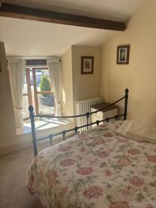 a bedroom with a bed with a floral bedspread and a window at The Old Stable in Abergavenny