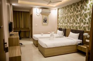 a hotel room with two beds and a television at Hotel Airport View in Pāsighāt