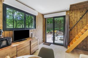 a living room with a tv and sliding glass doors at Cabane Spa - Noyers - Proche Sarlat in Jayac