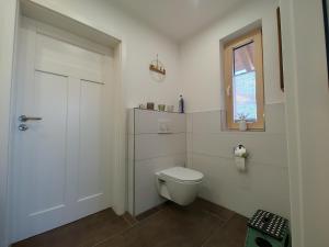 a white bathroom with a toilet and a window at Ferienwohnung Landliebe in Reichertsried +18 photos
