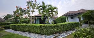 a house with a hedge in front of a yard at Siri Thai Lodges in Hua Hin