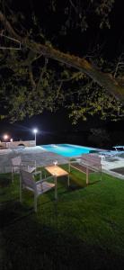 two benches and a table in front of a pool at night at Casa Relax Isabelle in Alberobello