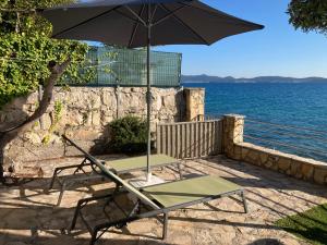 a chair sitting under an umbrella next to the ocean at House Private beach in Bibinje