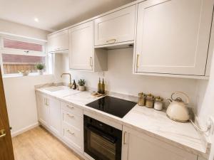 a kitchen with white cabinets and a sink and a tea kettle at Golden Sands Escape Weymouth Entire House in Wyke Regis