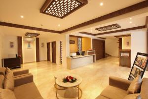 a living room with couches and a table and a counter at Hotel Salkara Chavakkad in Manattala
