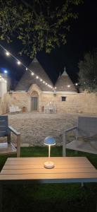a table with a stool in front of a building at night at Casa Relax Isabelle in Alberobello