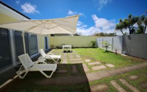 a patio with two chairs and an umbrella at Garden House 2 in São Vicente Ferreira