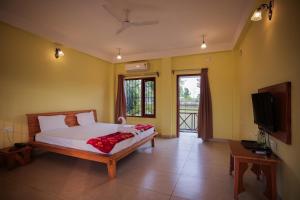 a bedroom with a bed and a flat screen tv at Resort Bihanga in Chālsa Mahābāri