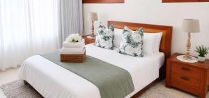 a bedroom with a large white bed with flowers on it at Sunset Sails 2 Apartment in Langstrand